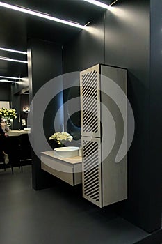 Elegant black room with white washbasin and wall cabinet for bathroom accessories