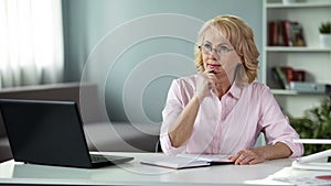 Elegant blond lady in eyeglasses planning day, female freelancer working home