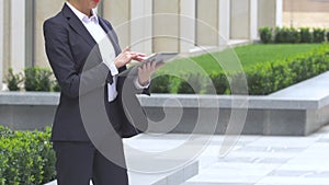 Elegant blonde business woman with tablet computer near office building