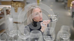 Elegant blonde in a kitchen utensils store. A woman chooses new wine glasses for a party.