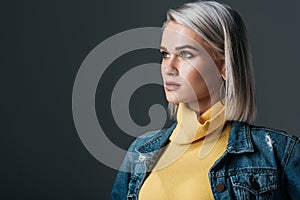 elegant blonde woman in yellow turtleneck and jeans jacket