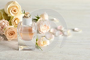 Elegant bottle of perfume and flowers on stone background, space for text