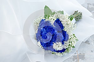 Elegant bouquet of blue roses on white textile background.