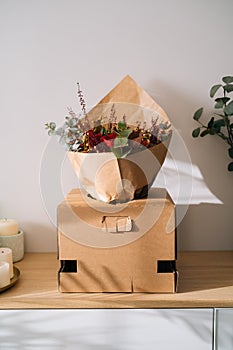 Elegant bouquet flower arrangement by florist in a box prepared for transport on a wooden table