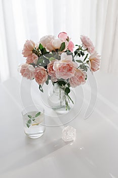 An elegant bouquet of fresh roses and placed by a light-filled window.