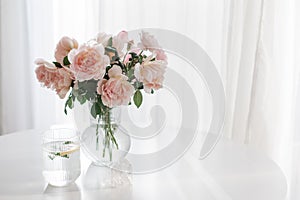 An elegant bouquet of fresh roses and placed by a light-filled window.