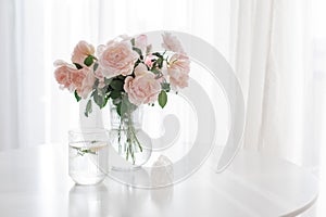 An elegant bouquet of fresh roses and placed by a light-filled window.