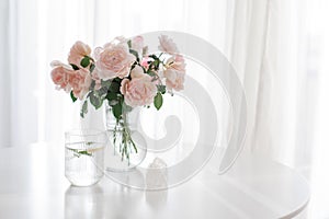 An elegant bouquet of fresh roses and placed by a light-filled window.