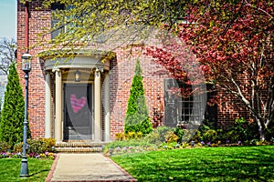 Elegant brick home with curved front entrance with pillars and beautiful landscaping and standing yard lanturn with Valentine