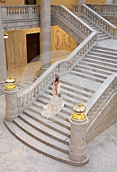 Elegant bride ascending large marble staircase