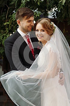 elegant bride and groom smiling in european city street at evening. luxury emotional wedding couple having fun. romantic sensual