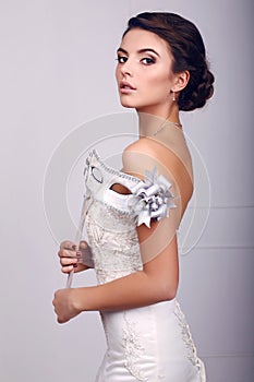 Elegant bride in wedding dress with mask in her hands