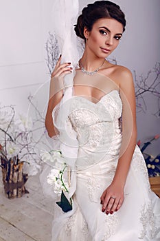 Elegant bride in wedding dress sitting on swing at studio