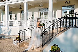 Elegant bride with wedding flowers bouquet, attractive woman in wedding dress. Young girl in a white dress goes the