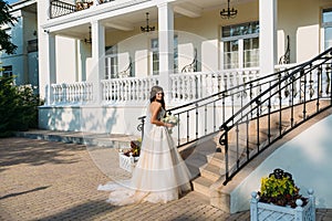 Elegant bride with wedding flowers bouquet, attractive woman in wedding dress. Young girl in a white dress goes the