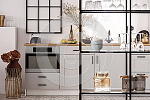 Elegant bright kitchen interior with white cupboards and black shelf