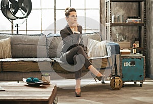 Elegant brunet business woman is sitting on couch in loft