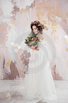 Elegant brunette girl bride with flowers. Beautiful young bride in a lush wedding wreath of fresh flowers