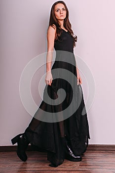 Elegant brunette lady posing in black evening dress. Studio shot