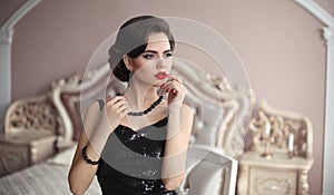 Elegant brunette with retro hairstyle posing in luxurious interior. Beauty fashion glamour girl portrait with red lips