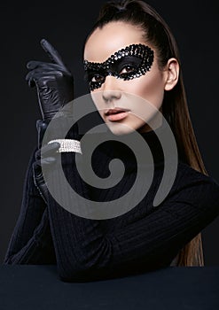 Elegant brunette woman in turtleneck sweater and sequins mask