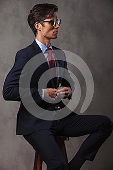 Elegant business man buttoning his suit while sitting