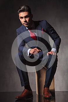 Elegant business man sitting on a wood box while thinking.