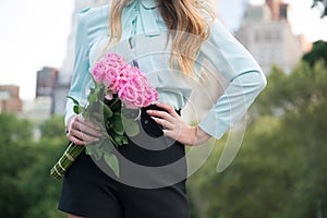 Elegant business woman holding roses bouquet against city background