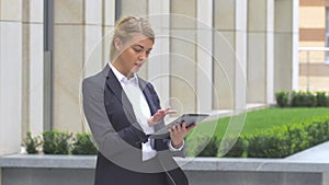 Elegant business woman with tablet computer near office building