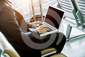 Elegant businessman checking e-mail on mobile phone while walking with suitcase inside airport