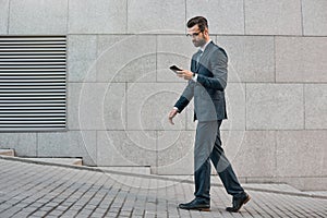 Elegant businessman hand holding and using a smart phone outdoors