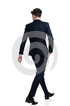 elegant businessman looking to side and walking with hand in pocket