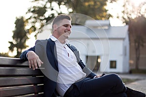 Elegant businessman sitting on a bench outdoors