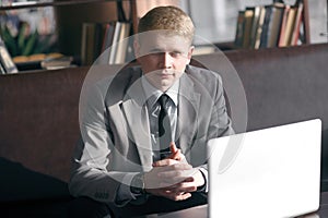 Elegant businessman sitting at desk with laptop