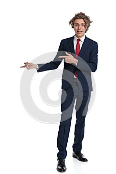 Elegant businessman in suit with curly hair pointing fingers to side