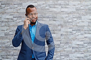 Elegant businessman in suit talking on phone against wall