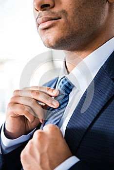 Elegant businessman in suit tying necktie