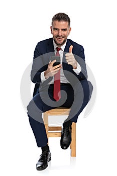 Elegant businessman with telephone making thumbs up gesture