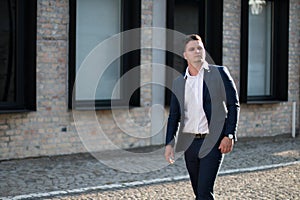 Elegant businessman walking between office buildings