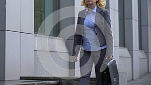 Elegant businesswoman walking by office building, governmental institution