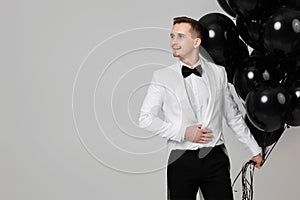 caucasian man in white suit tuxedo with black air balloons