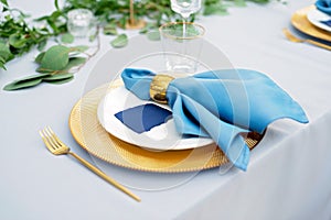 Elegant and chic wedding table setting in gold and blue colors and fresh flowers. Soft selective focus