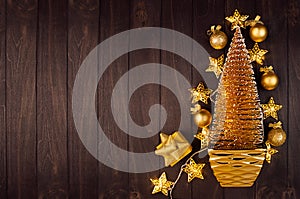 Elegant christmas background - golden christmas tree in bowl with warm stars lights garland  on dark brown wood board.