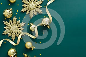 Elegant Christmas background with golden decorations, snowflakes, ribbon on green. Flat lay, top view