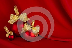 Elegant christmas background - traditional red christmas balls with gold shiny ribbon on scarlet smooth wavy silk, closeup.