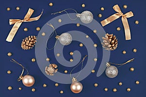 Elegant Christmas flat lay with golden and silver tree ornament baubles, ribbons and fir cones on blue background