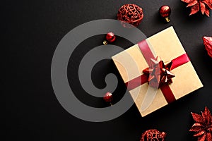 Elegant Christmas gift box with red ribbon, red decorations, balls on black background. Christmas present top view. Flat lay