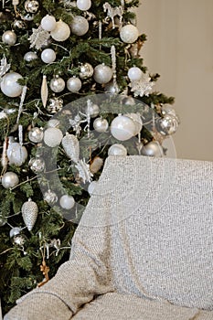 Elegant Christmas tree beside a cozy, modern chair.