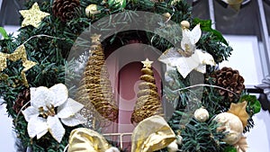 Elegant christmas wreath with white flowers, golden ribbon on red door.