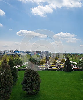 An elegant city park under a blue sky with white clouds. Top view of a beautiful park in early spring. Urban landscape. Green lawn